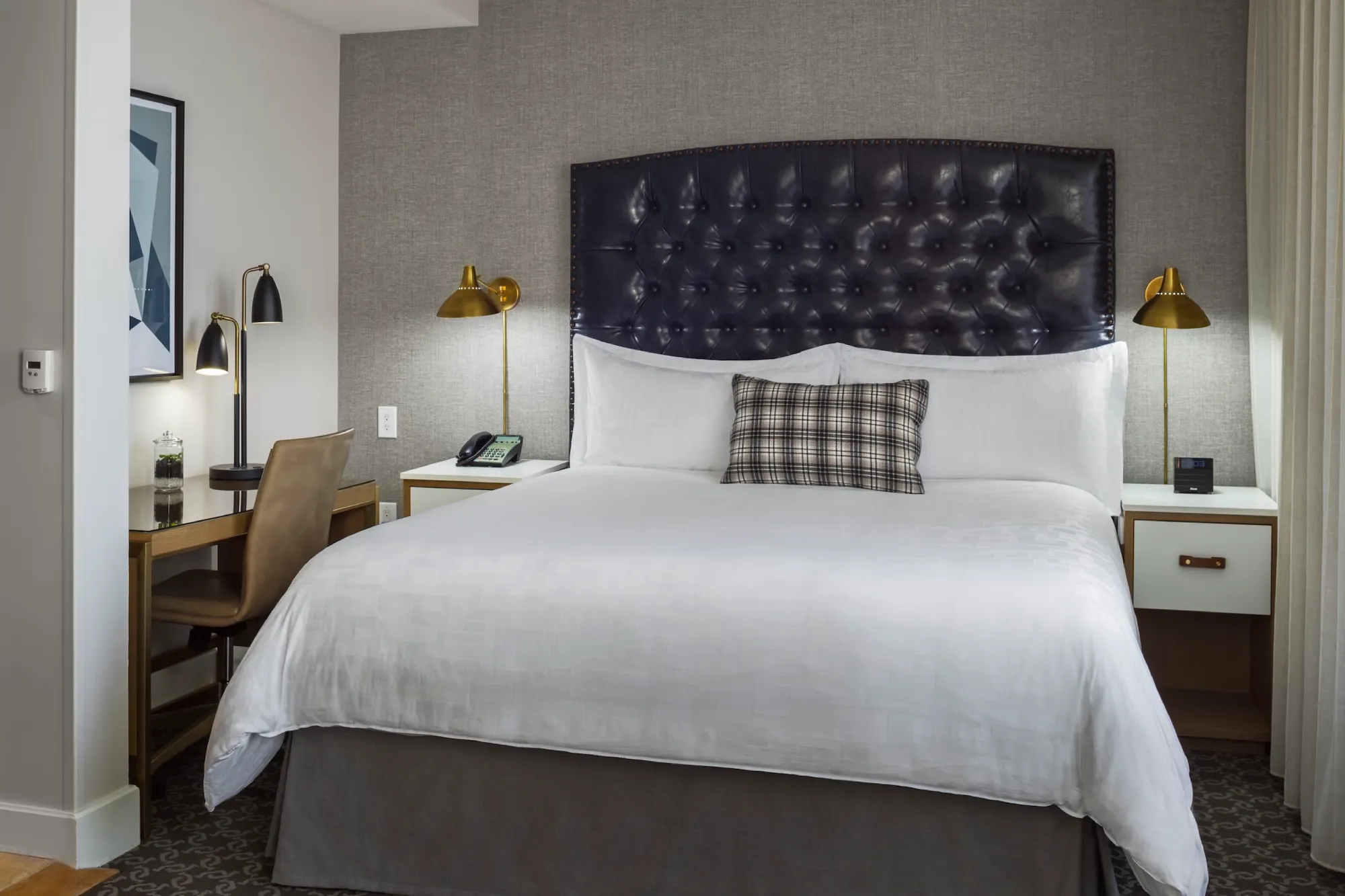 a bed with a black headboard and two lamps