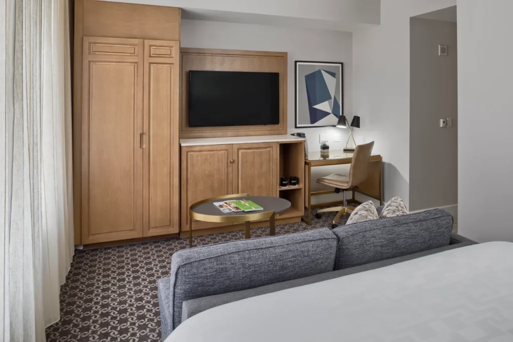 a hotel room with a bed, desk, and television
