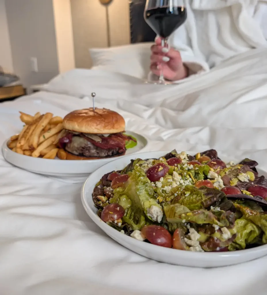 a plate of food and a glass of wine on a bed