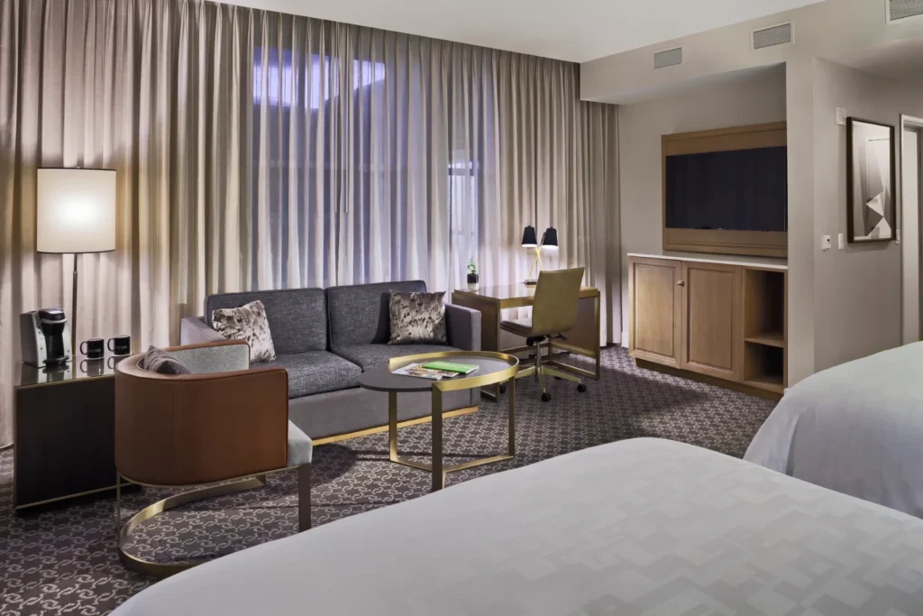 a hotel room with a couch, chair, desk and television