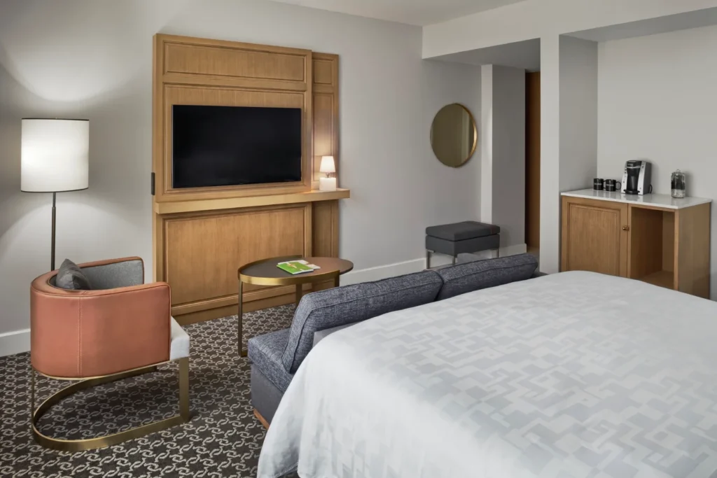 a bed room with a neatly made bed and a flat screen tv