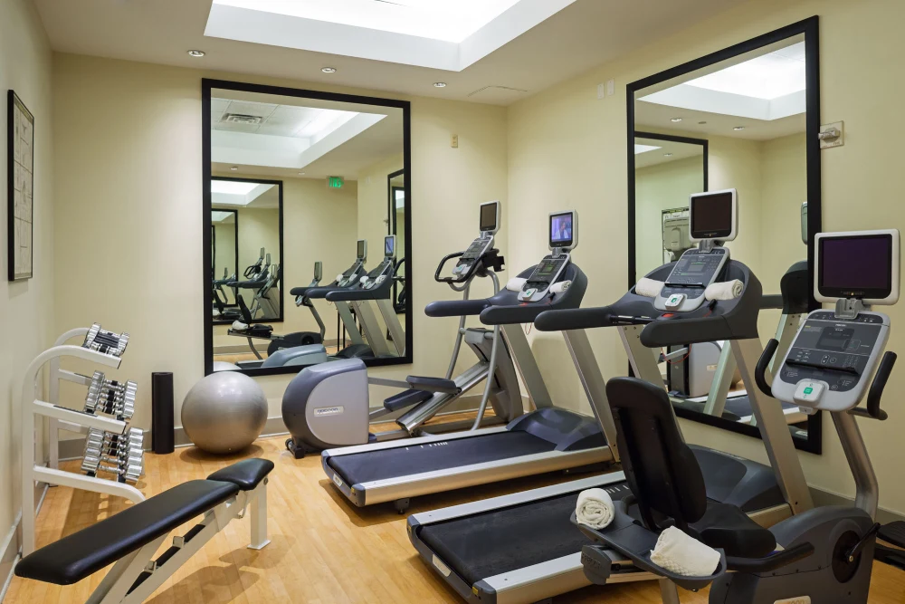 a gym with treadmills, exercise bikes and mirrors