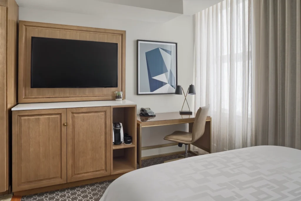 a bedroom with a bed, desk and television