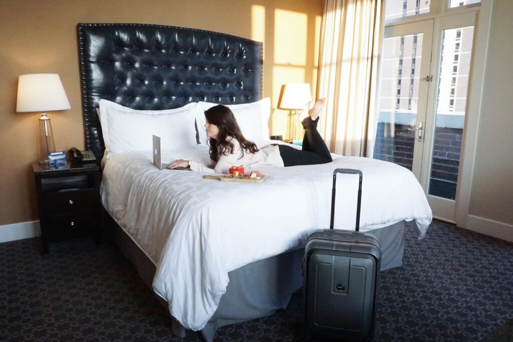 woman on hotel bed working on laptop