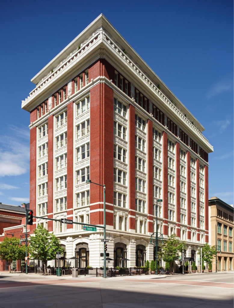A tall, multi-story building with a red brick and white facade, featuring numerous windows and a flat roof.