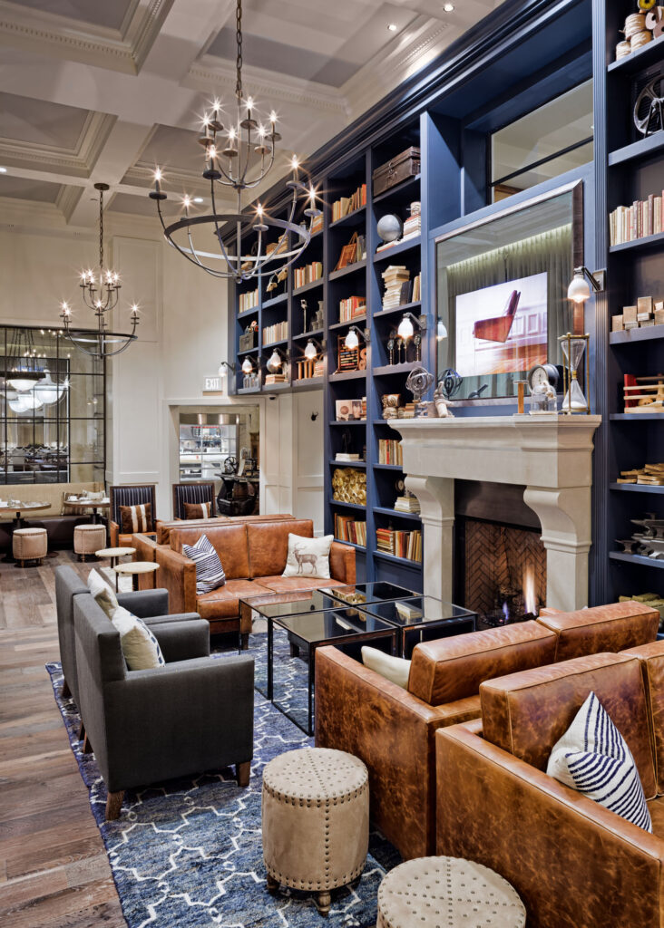 A well-lit living room with a fireplace, bookshelves, and leather furniture.