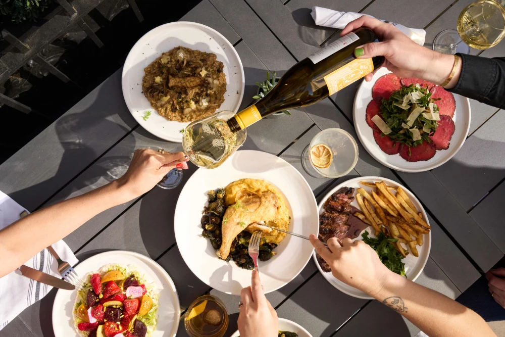 a group of people sitting around a table with plates of food