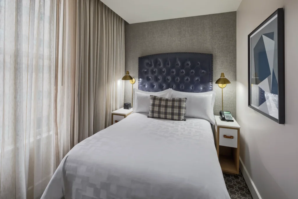 a bedroom with a bed, two lamps and a picture on the wall