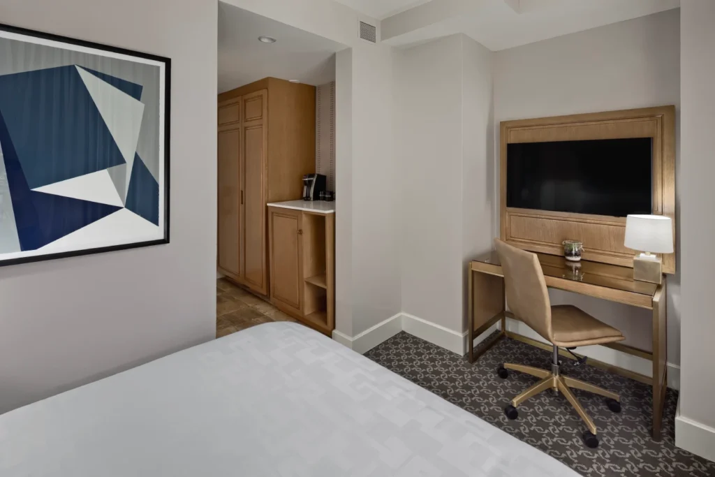 a bedroom with a bed, desk and television